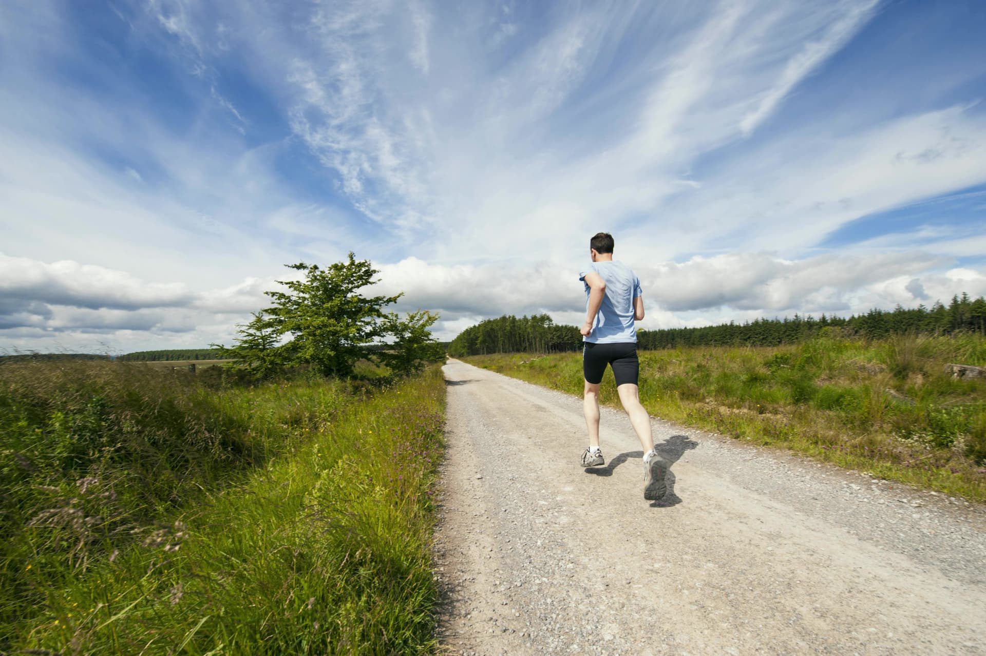 A man running along an open country road under a big sky.