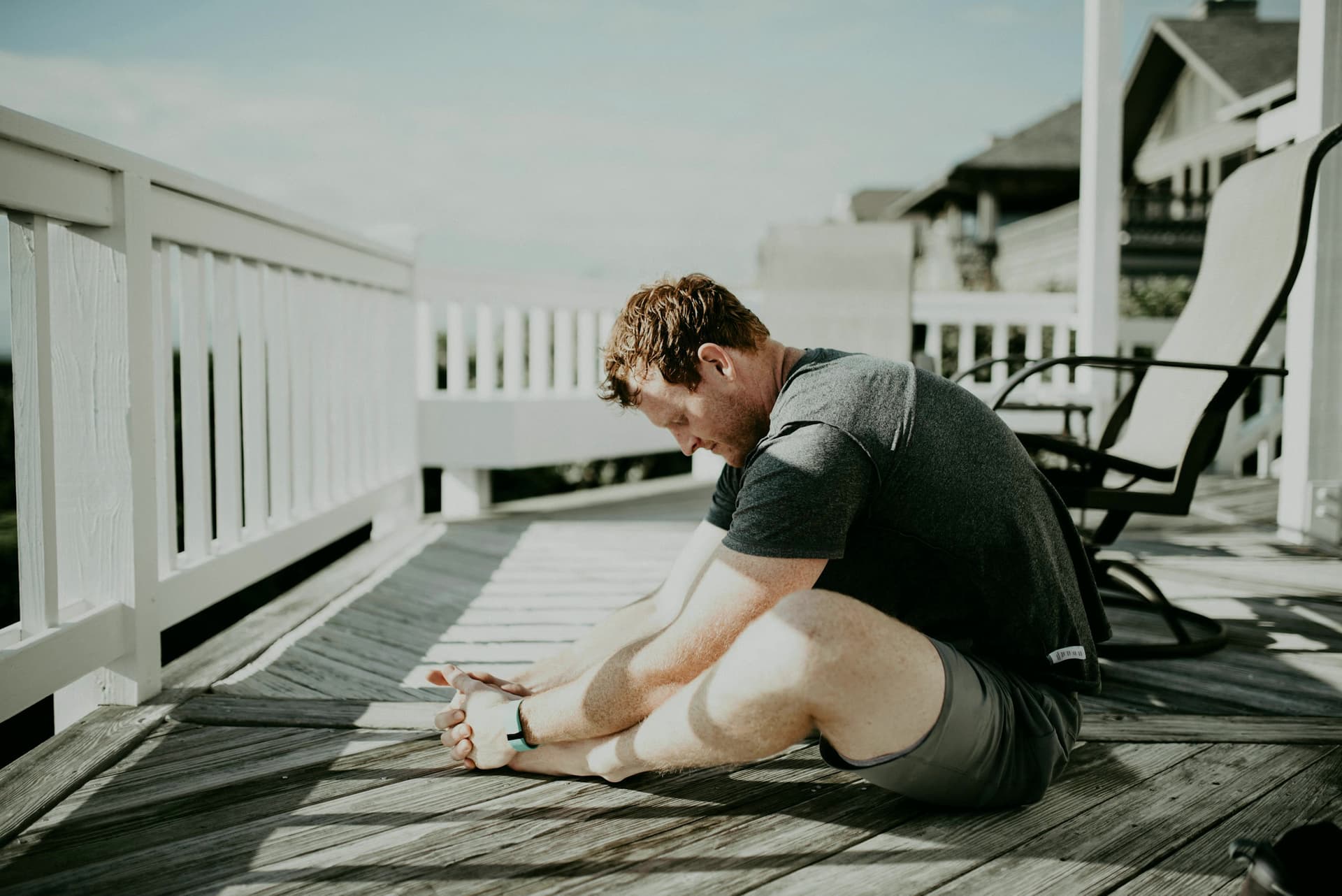 A man stretching on a sunny wooden deck.